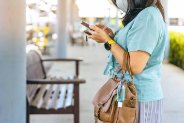 Corona Virüsü 'nü (Covid-19) öldürmek için mini taşınabilir alkol jeli şişesi bir kadının deri omuz çantasına asılıp alışveriş merkezine gider. Yeni normal yaşam tarzı. Alkol jeline odaklan