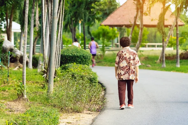 Back view portrait of a Asian elderly woman wears protective face mask to protect from Corona Virus(COVID-19)walking and jogging in public park.Mature woman enjoying Peaceful nature.Healthcare concept