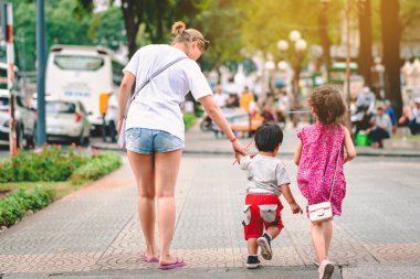 Güneşli bir yaz gününde, küçük oğluyla birlikte kaldırımda yürüdüğü arka manzara.