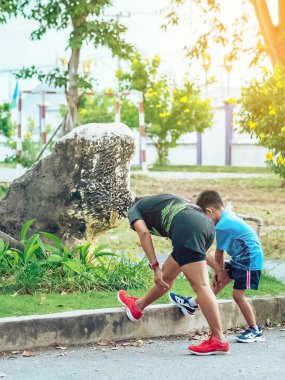 Sportif ve mutlu bir annenin oğlunu bahçede egzersiz yapmadan önce esneme hareketleri yaparken izlemesi. Atletik aile dışarıda birlikte egzersiz yapıyor. Çocuk bakımı spor aktivitesi konsepti