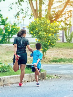 Sportif ve mutlu bir annenin oğlunu bahçede egzersiz yapmadan önce esneme hareketleri yaparken izlemesi. Atletik aile dışarıda birlikte egzersiz yapıyor. Çocuk bakımı spor aktivitesi konsepti