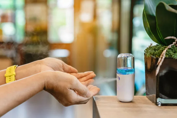 Alcohol nano mist sprayer for hand cleaning to prevent the spread of the Corona virus (Covid-19) to serve customers at coffee shop. Modern health technology. New normal lifestyle. Selective focus