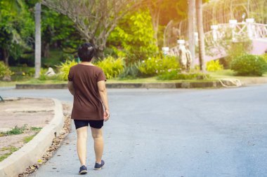 Halk parkında yürüyen ve koşan Asyalı yaşlı bir kadının arka plan portresi. Doğada kıdemli koşucu. Yaşlı kadın barışçıl doğanın tadını çıkarıyor. Sağlık hizmetleri kavramı