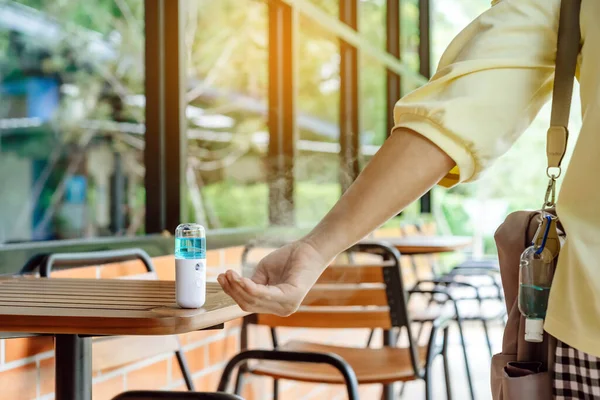 Alcohol nano mist sprayer for hand cleaning to prevent the spread of the Corona virus (Covid-19) to serve customers at coffee shop. Modern health technology. New normal lifestyle. Selective focus