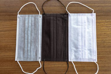 Coronavirus (Covid-19) için cerrahi maskeli gri, siyah ve beyaz tahta masa. Çok renkli güzel maskeler. Yeni normal yaşam tarzı. Seçici odak