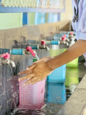 Okula gitmeden önce Corona virüsünün (Covid-19) yayılmasını önlemek için el yıkama alanı. Sağlık hizmeti konsepti. Yeni normal eğitim. Musluğa seçici odaklanma