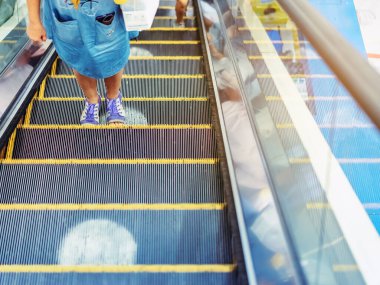 Coronavirus 'un alışveriş merkezindeki Covid-19 salgını sırasında sosyal mesafeyi korumak için yürüyen merdiven zemininde beyaz daireler sembolü uyarısı. Yeni normal yaşam tarzı