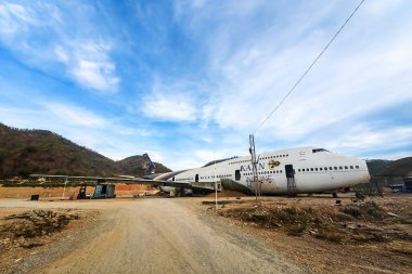KANCHANABURI, THAILAND-APRIL 6. 2025: Tayland Havayolları 'ndan gelen eski bir ticari uçakla dağlarla çevrili yeni ve güzel bir yer için yapılan yenileme çalışmalarına bakın..