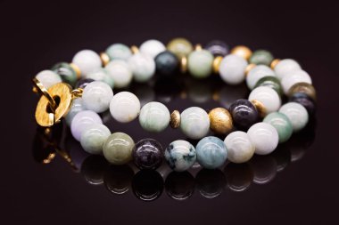 Bir dize içine bir kolye, bir parlak siyah yüzeyi bir yansıması ile sinirli Birmanya jade boncuk