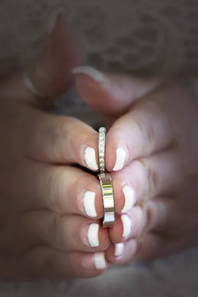 Wedding rings held between the fingers of the bride