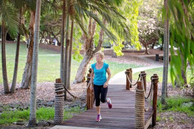 Açık havada bir ahşap köprü bir parkta koşu çalışan giyim fitness egzersiz kadın kıdemli