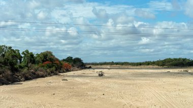 Ön plan ve mavi bulutlu gökyüzü güç hatları ile bir köprü gibi bir kuraklık sırasında su ile Kuru dere yatağı