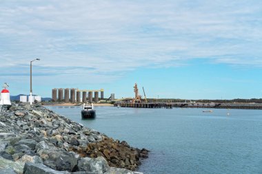 İçinde belgili tanımlık geçmiş bir endüstriyel wharf bir taş duvar üzerinde oturan bir deniz feneri doğru yelken tekne römorkör
