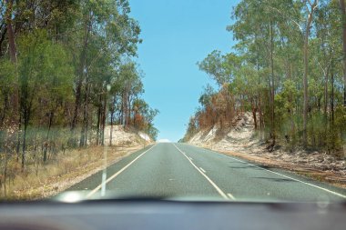 Hareket eden bir aracın içinde görülen kireçli toprak kesme bir uzun asfalt yol