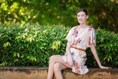 O güneşin altında güzel bir bahçe içinde oturur gibi sevinçle gülümseyen güzel genç bayan