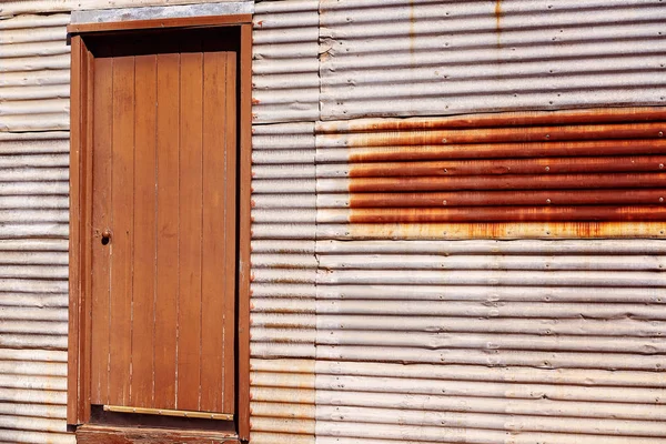 Porta de madeira vintage na parede de ferro ondulado — Fotografia de Stock