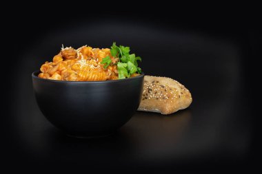 Siyah bir arka plan üzerinde makarna ve ekmek bir kase