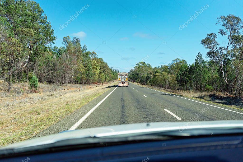 Clermont, Queensland, Australia - October 2019: A semi trailer on a country highway as seen through the windscreen of the car travelling behind