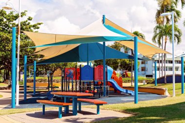 Gölge satışı ve yakınlarda piknik masası olan çocuklar için renkli bir oyun alanı.