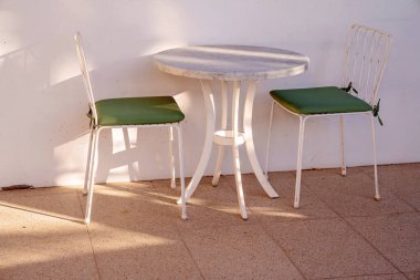 Güneşli bir yaz gününde gölgeli bir yerde dışarıda yemek yemek için bir masa ve sandalyeler.