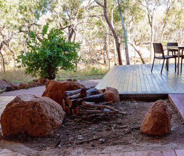 Çalılıktaki bir Avustralya restoranında yemek masaları ve sandalyelerin yanında bir şömine.