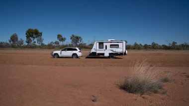 Undara 'dan Townsville otoyoluna, Queensland, Avustralya - Haziran 2020: Araba ve karavan toprak ve tozun arasına park edilmiş.