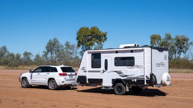 Undara 'dan Townsville otoyoluna, Queensland, Avustralya - Haziran 2020: Araba ve karavan toprak ve tozun arasına park edilmiş.