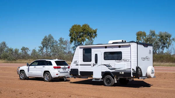 Undara 'dan Townsville otoyoluna, Queensland, Avustralya - Haziran 2020: Araba ve karavan toprak ve tozun arasına park edilmiş.
