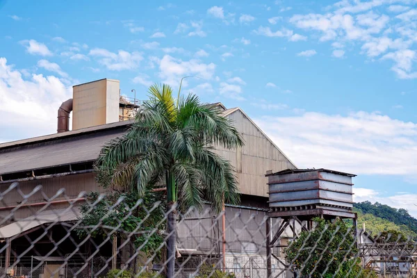ワイヤーフェンスの後ろに見えるサトウキビ製粉工場 — ストック写真