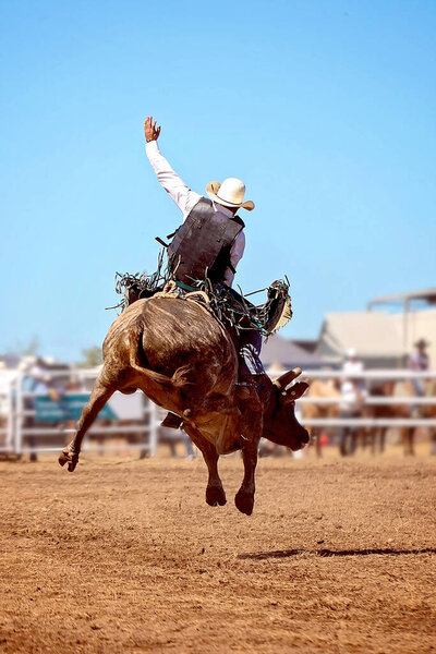 A cowboy riding a bucking bull at an Australian country rodeo