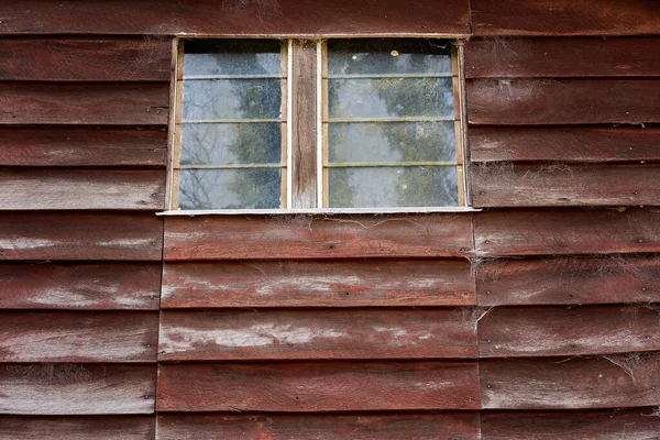 Louvered windows in an old cobweb covered timber wall of an ancient and abandoned country community hall