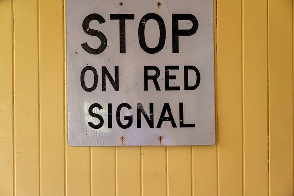 在黄色木墙上的红色信号灯上停车 — 图库照片
