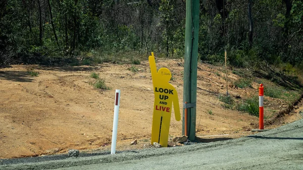 Look Up And Live warning of power lines person shaped sign at roadworks