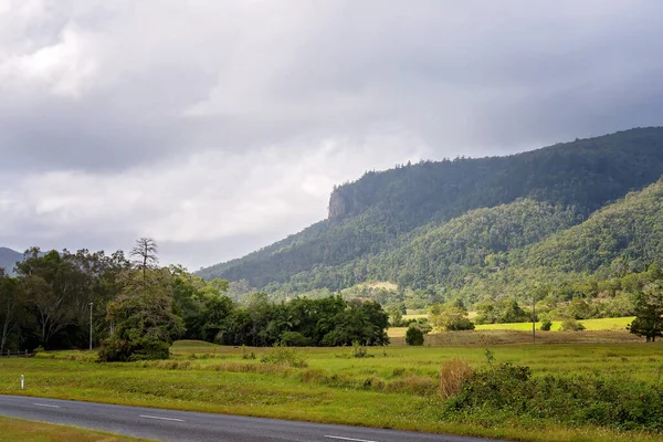 Bulutlar ve güneş ışığı açık havada fırtınalı bir sabahta arazide yol alıyorlar.