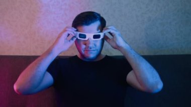 Kanepede oturan bir adam yavaşça teyp gözlüğü takıyor..