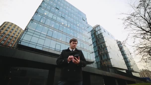 Joven hombre de negocios hablando por teléfono en un fondo de un centro de negocios . — Vídeos de Stock