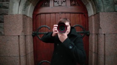 Siyah ceketli genç bir fotoğrafçı eski kapıların arka planında fotoğraf çekiyor..