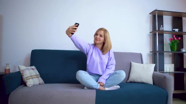 Flickan på soffan tar en selfie.. — Stockvideo