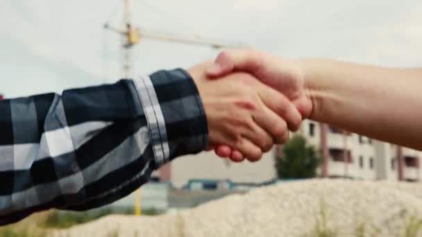 Крупним планом чоловічі руки вітають один одного на будівельному майданчику . — стокове відео