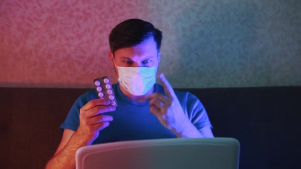 Een gemaskerde man in quarantaine raadpleegt via videolink hoeveel tabletten te gebruiken. — Stockvideo