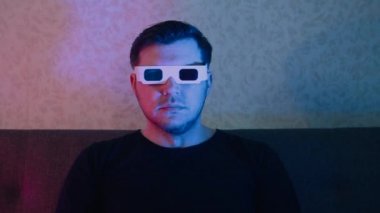Kanepede oturmuş, müzik seti takmış bir adam duygusal olarak televizyon izliyor..