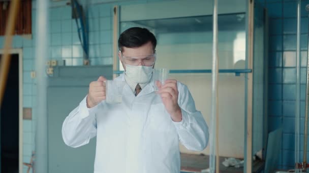 Un travailleur médical en costume médical et des lunettes tient dans ses mains des cônes faisant des tests . — Video