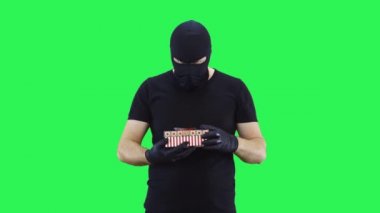 Maskeli adam hediye kutusunu yavaşça açıyor. Kar maskesi. Yeşil ekran arka plan..