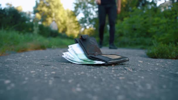 Un sac à main avec de l'argent repose sur le sol, un passant le ramasse . — Video