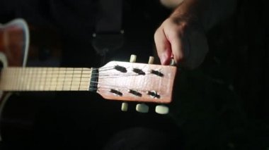 Genç gitarist akustik gitarı yakından ayarlıyor..