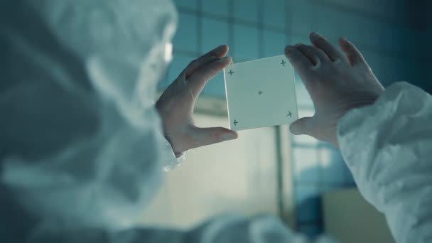 Šablona pro sledování se sledovacími body laboratorního asistenta v lékařském obleku a lékařskou maskou vyšetřující lékařské sklo. — Stock video