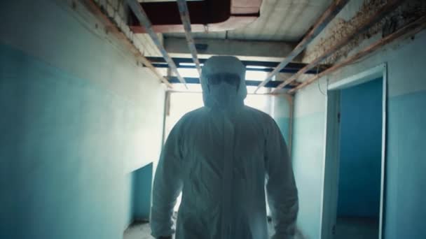 Un hombre con traje médico protector y gafas está caminando por el pasillo. . — Vídeos de Stock