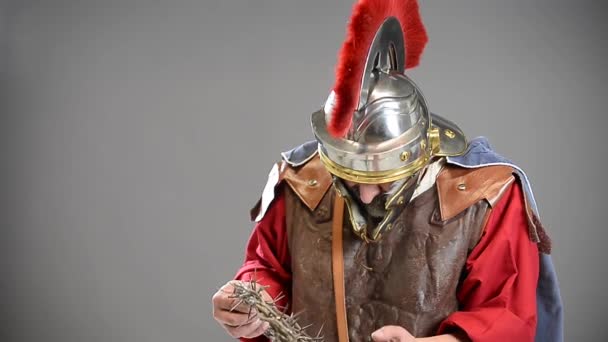 灰色の背景に隔離されたとげの王冠を保持しているローマの兵士 — ストック動画