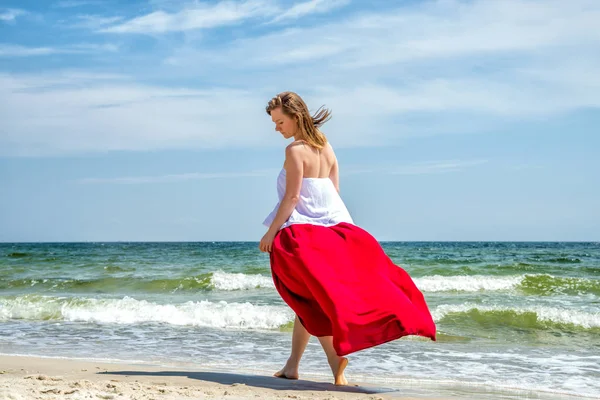 Menina bonita em vestido vermelho pelo mar . — Fotografia de Stock