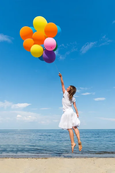 Vrouw met baloons springen op de zee — Stockfoto